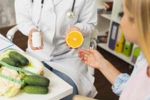 A woman in a doctor's office holding an orange and a pill, emphasizing the role of dietitians in managing COPD.
