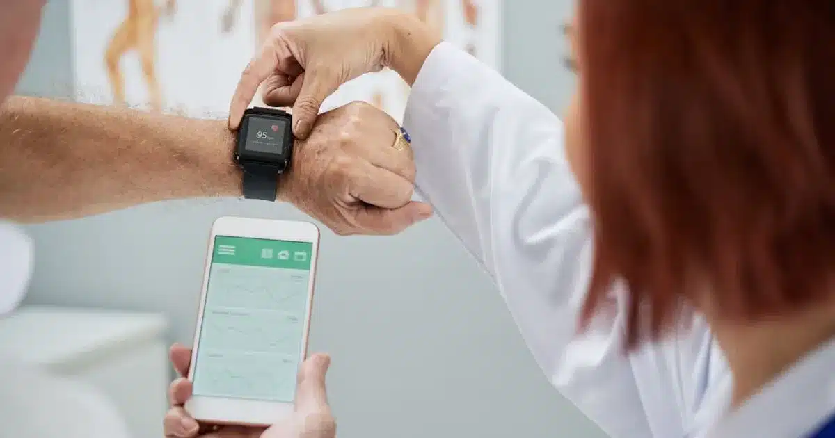 A person wearing a smartwatch displays a health metric, while another person checks related data on a smartphone.