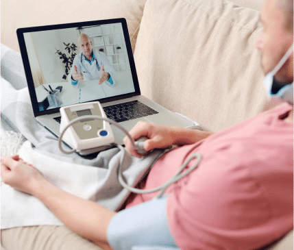 A person using a blood pressure monitor at home while consulting with a doctor via a video call on a laptop, perfect for showcasing on your landing page to boost SEO in v2.