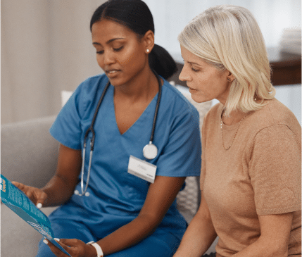 A healthcare professional in blue scrubs shows a pamphlet to a seated woman with short blonde hair, creating an inviting scene worthy of a landing page.