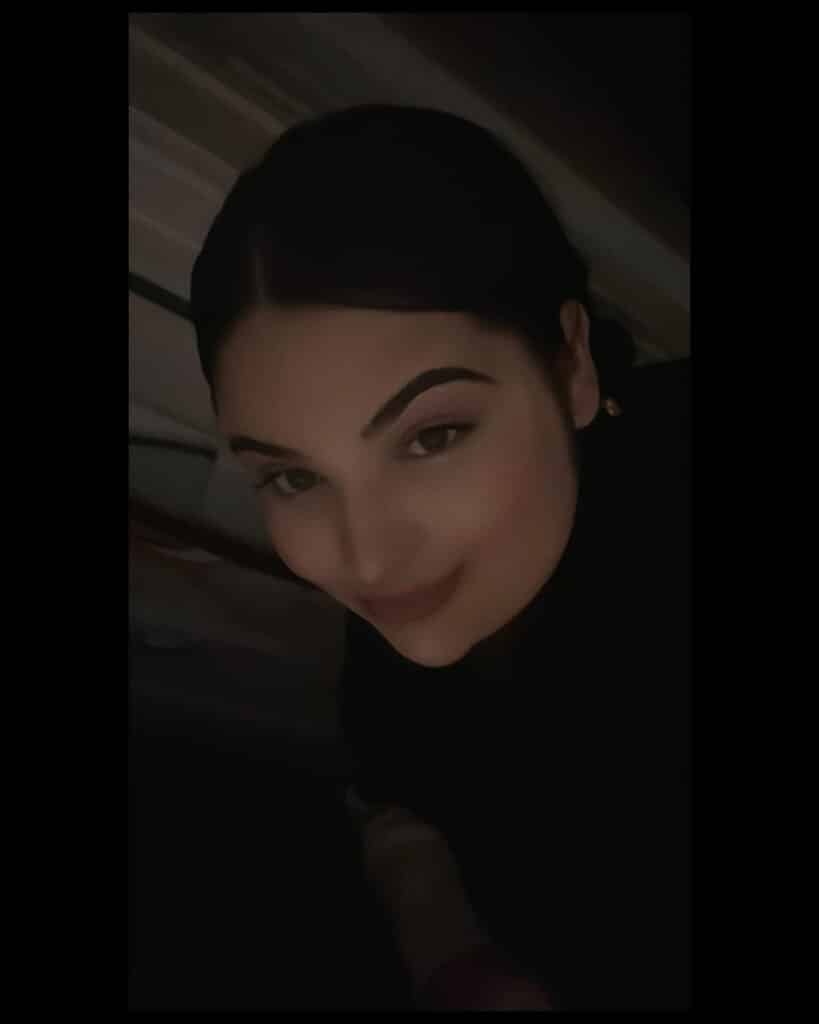 A person with dark hair and defined eyebrows is smiling softly at the camera in a dimly lit setting, radiating quiet confidence—one of our many Success Stories.