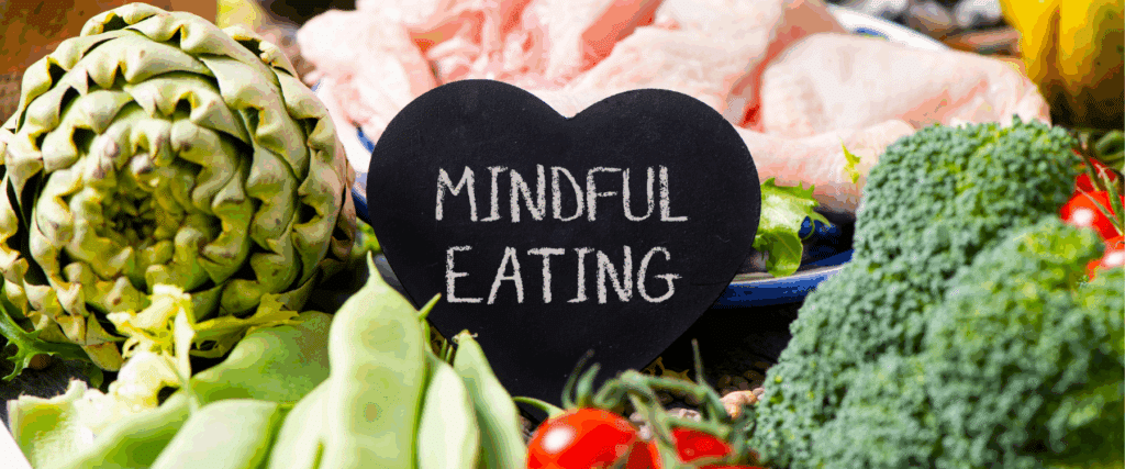 A chalkboard heart with "Mindful Eating" surrounded by fresh vegetables, beans, broccoli, tomato, and raw meat—perfect inspiration to nourish your body through mindful nutrition.