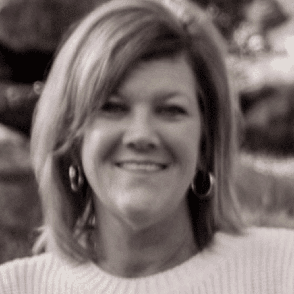A woman with shoulder-length hair, wearing hoop earrings and a light-colored sweater, smiles outdoors in this black and white photo—one of many inspiring weight loss success stories.